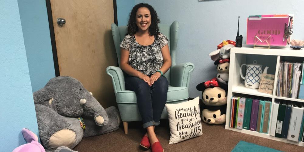Giselle Ortiz, case manager at Holbrook Indian School, posing in the chair in her office where students usually sit. (Andrew McChesney / Adventist Mission)