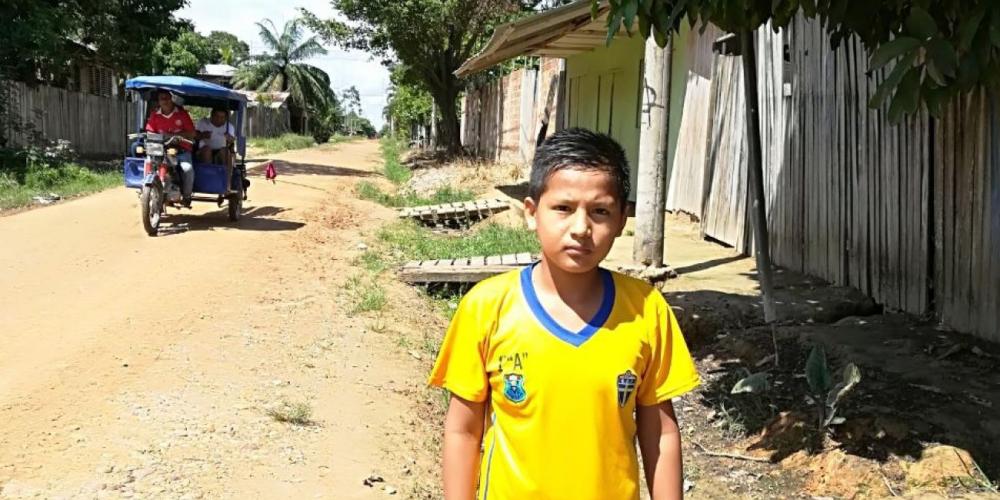 Renzo Jesus Arenas Flores, 11, standing beside a road in Pucallpa, Peru. On Sabbath, he and his father walk along the road to visit the homes of people who missed church. (Adventist Mission)