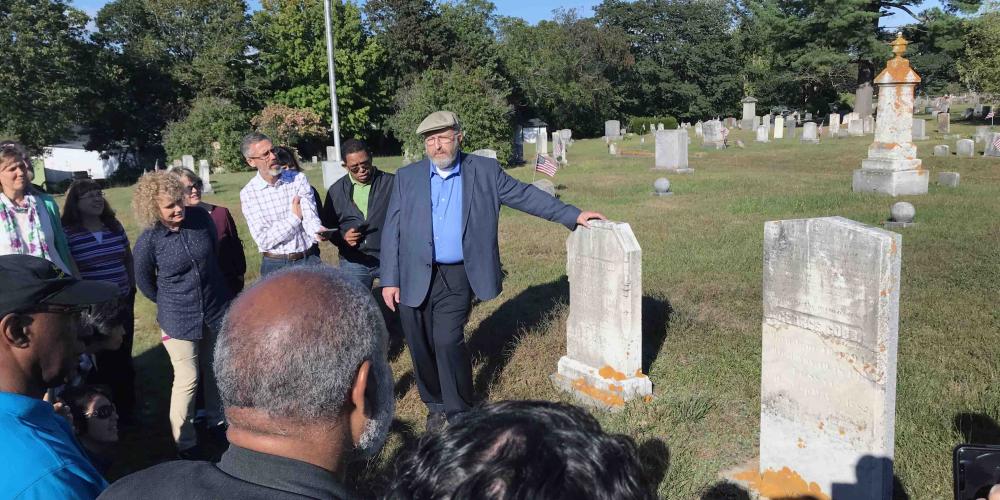 James Nix, center, director of the Ellen G. White Estate, showing George Cobb’s tombstone to a General Conference tour group in a cemetery in Brunswick, Maine, on Sept. 13, 2018. (Clinton Wahlen)