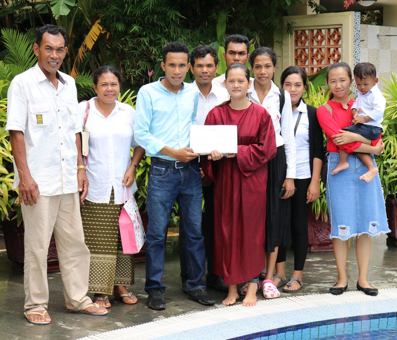 Men Marina, fourth from right, wearing a backpack and crocs, posing with her parents, siblings, and other relatives. (Family photo)