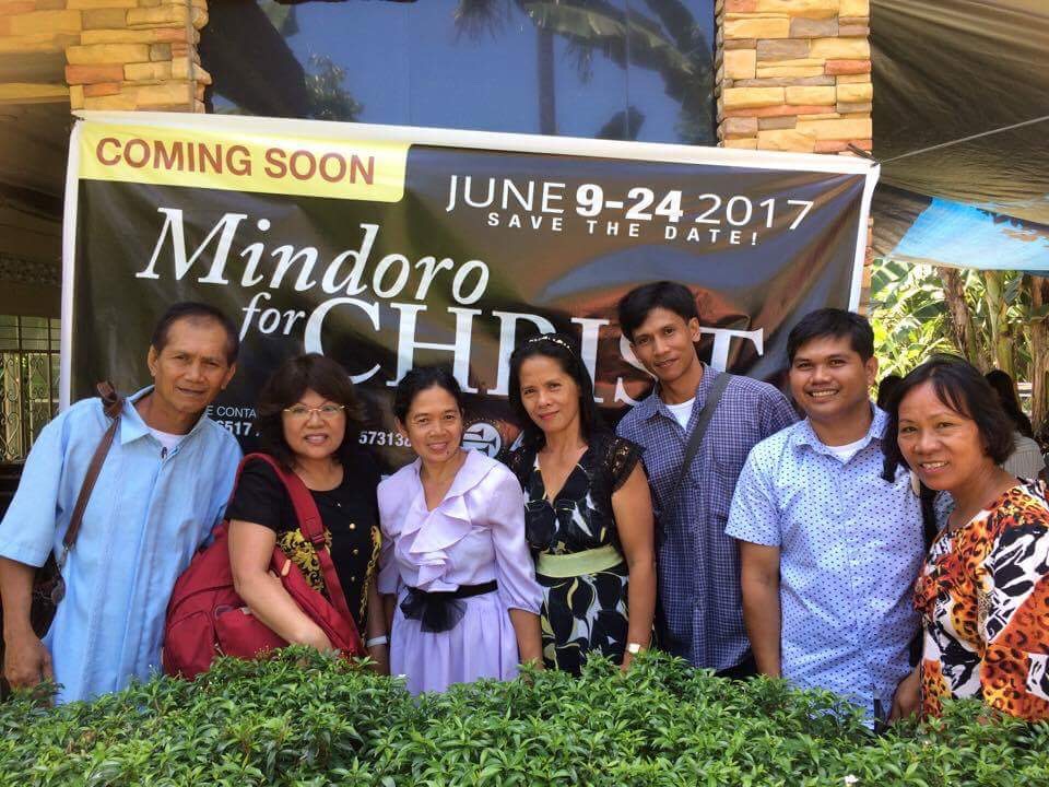 Emma Ballesteros, second left, standing near a poster heralding the Mindoro evangelistic meetings in the Philippines. (Courtesy of Emma Ballesteros)